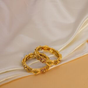 Luxurious gold bangles on a satin backdrop, showcasing intricate jewelry design.